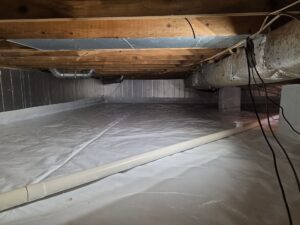 Crawlspace encapsulation with sealed plastic liner, exposed ductwork, and drainage system, illustrating moisture control and protection in Maryland homes.