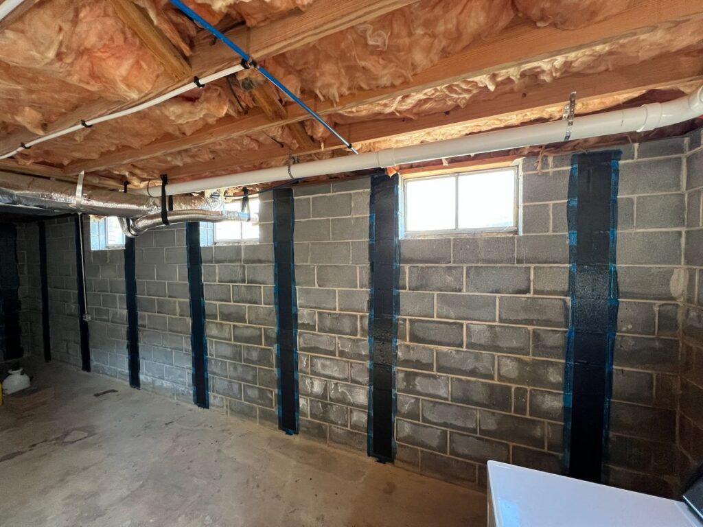 Carbon fiber straps reinforcing a cracked concrete block basement wall during Rockville foundation repair to stabilize structural movement.